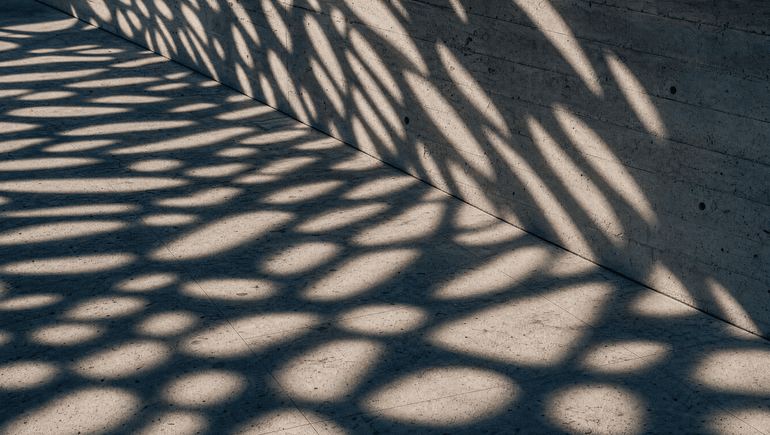 The Umbra canopy shadow pattern falling across stone paving and the pool
