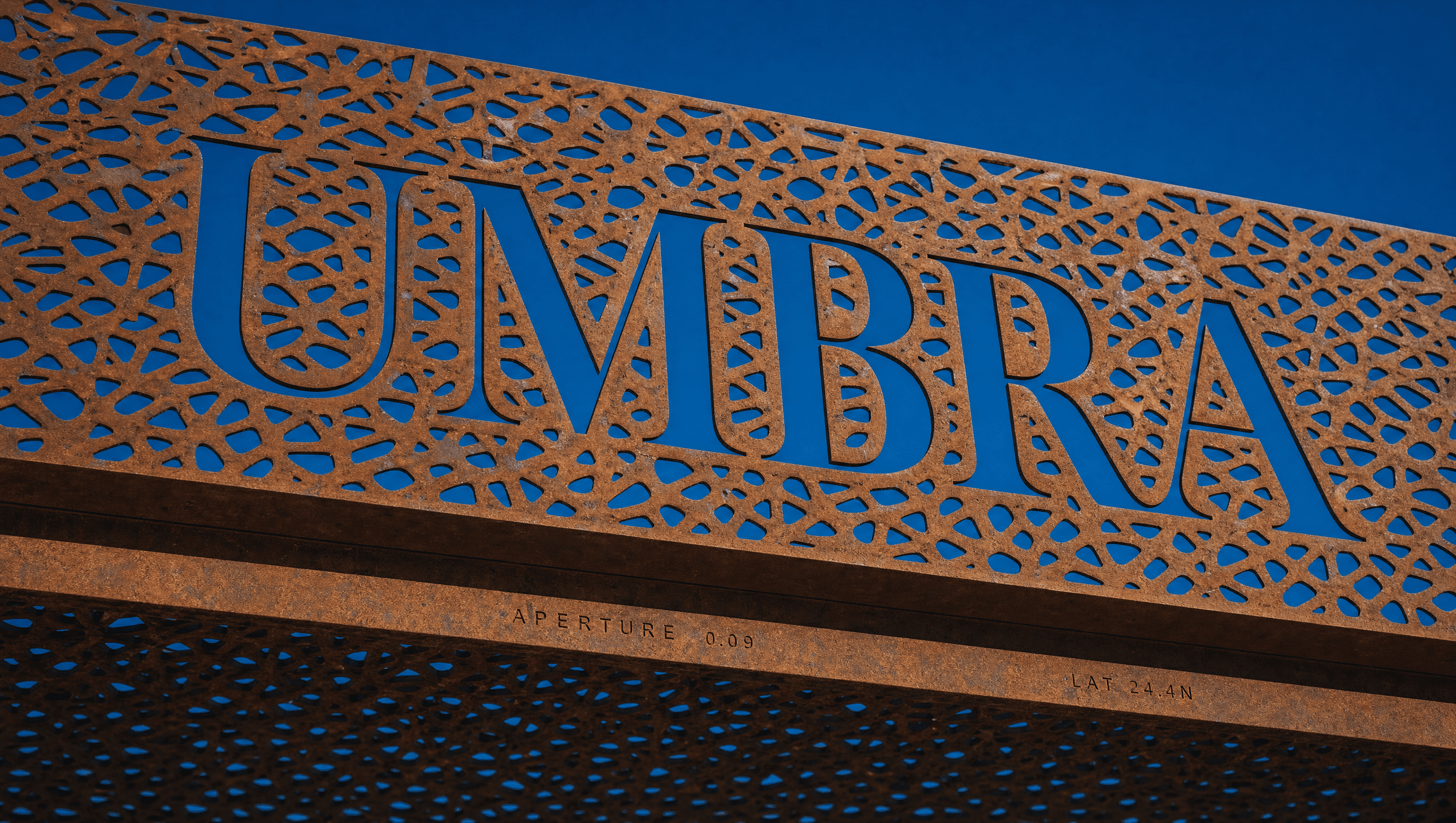 The Umbra wordmark cut clean through the perforated copper canopy, letters made of daylight
