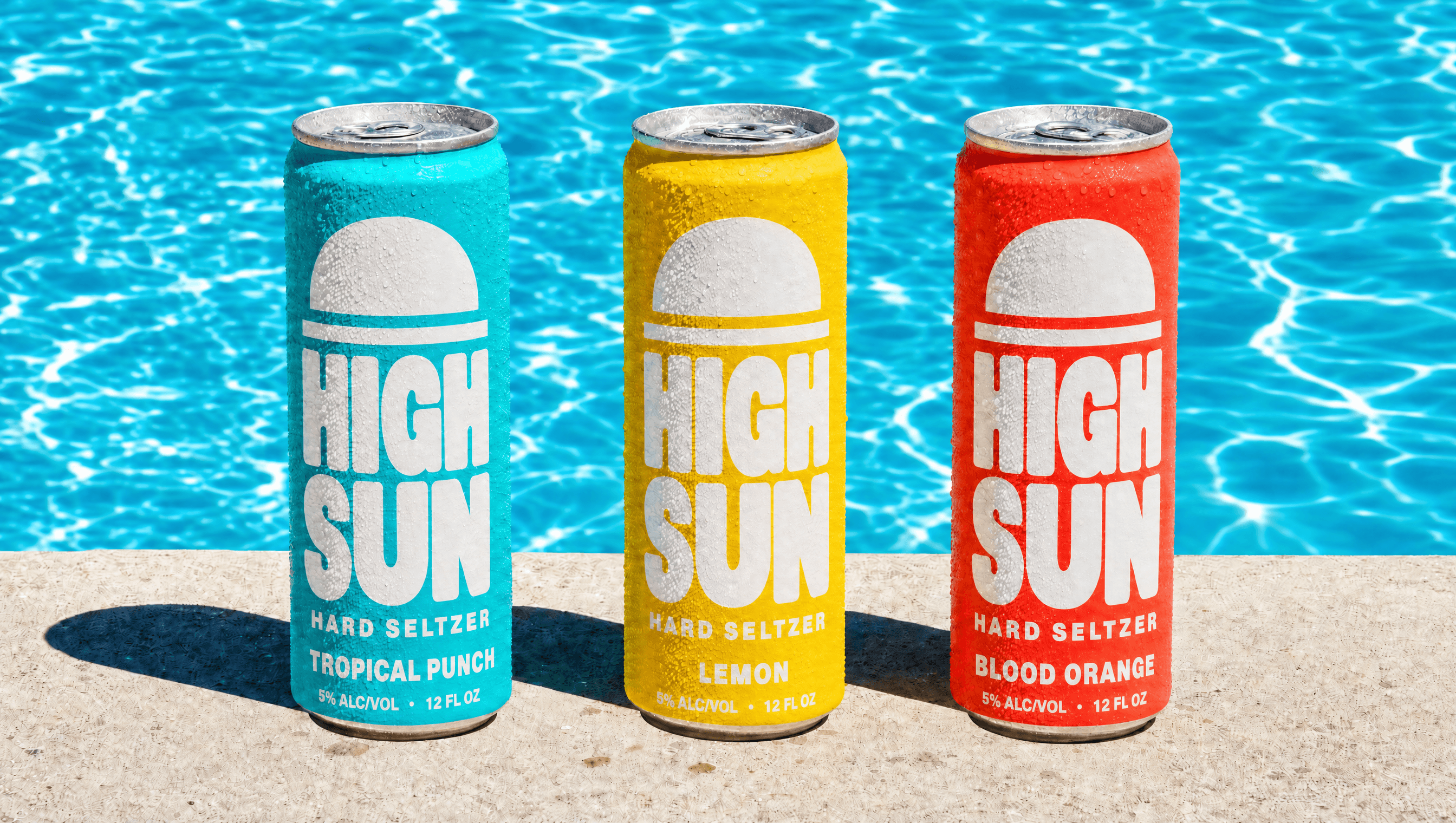 Three High Sun hard seltzer cans on a pool edge in hard sunlight