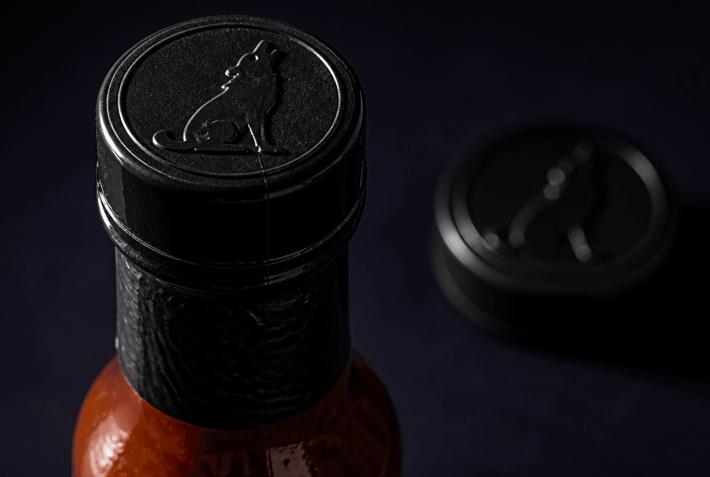 Howler bottle cap with the coyote struck into the moulded black plastic