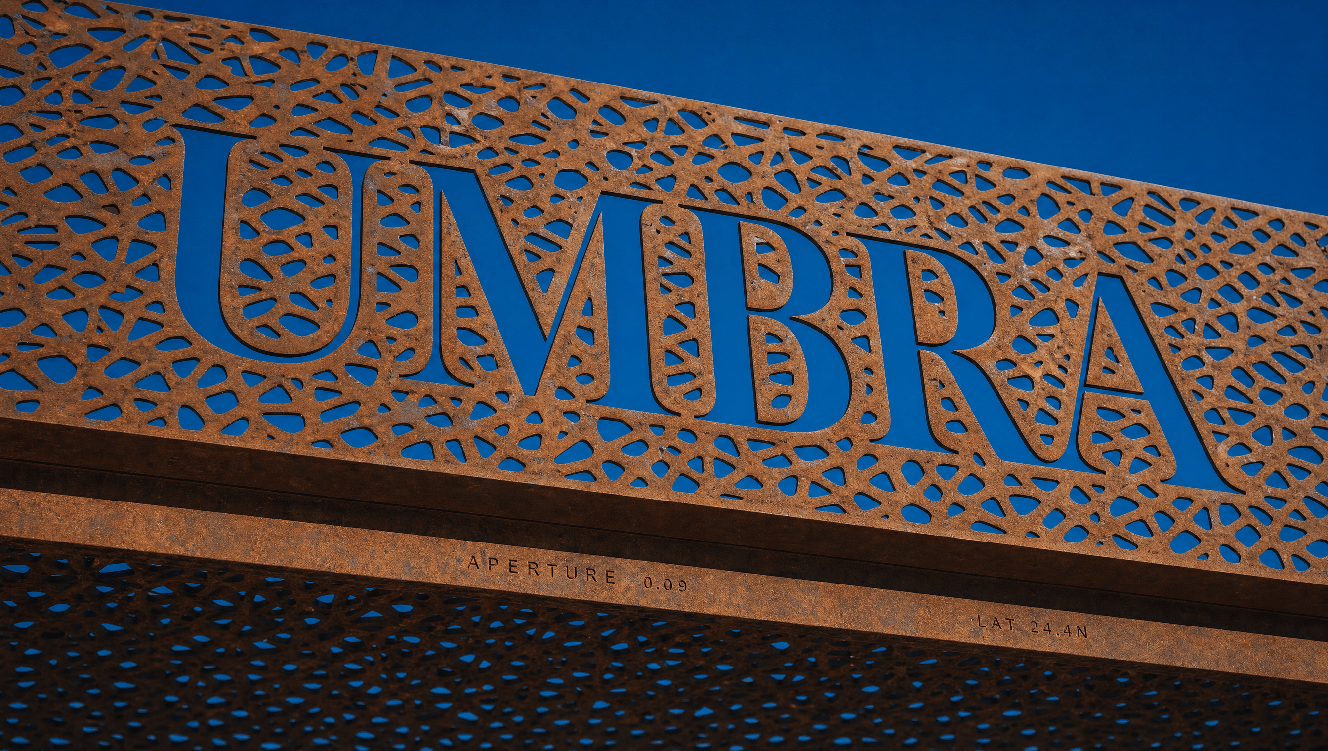 The Umbra wordmark cut clean through the perforated copper canopy, letters made of daylight